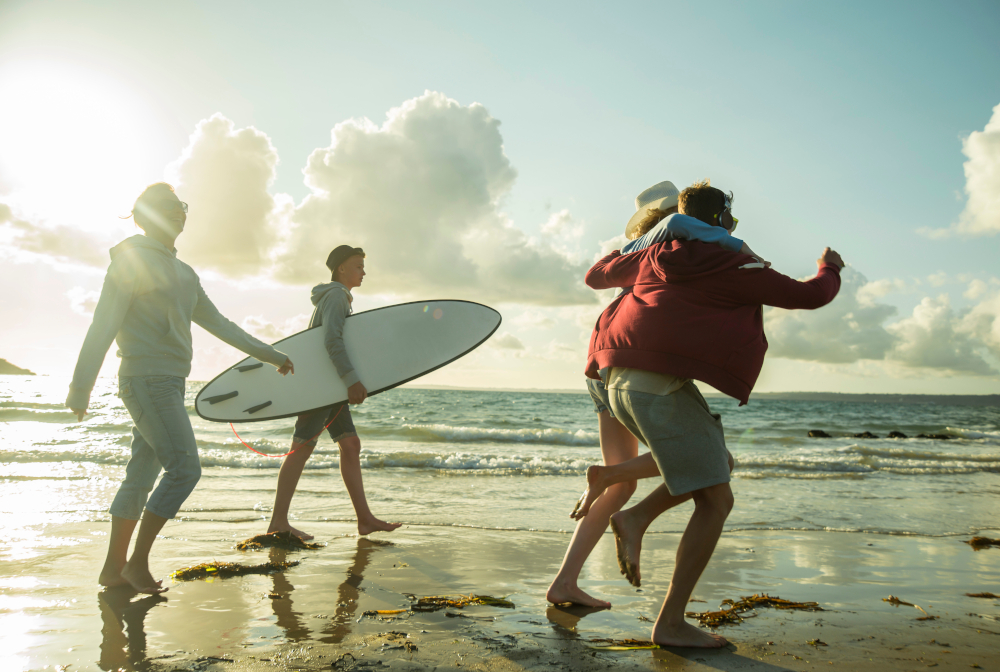 Woman And Three Teenagers Walking At Waterside Of The Sea