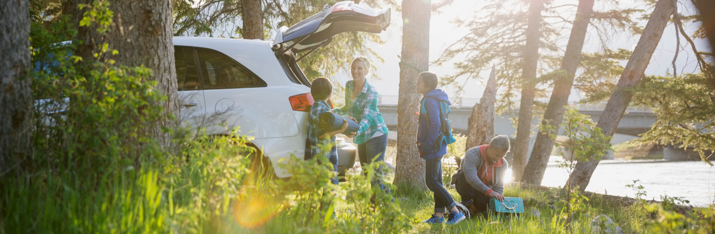 Family Unpacking Car At Campsite