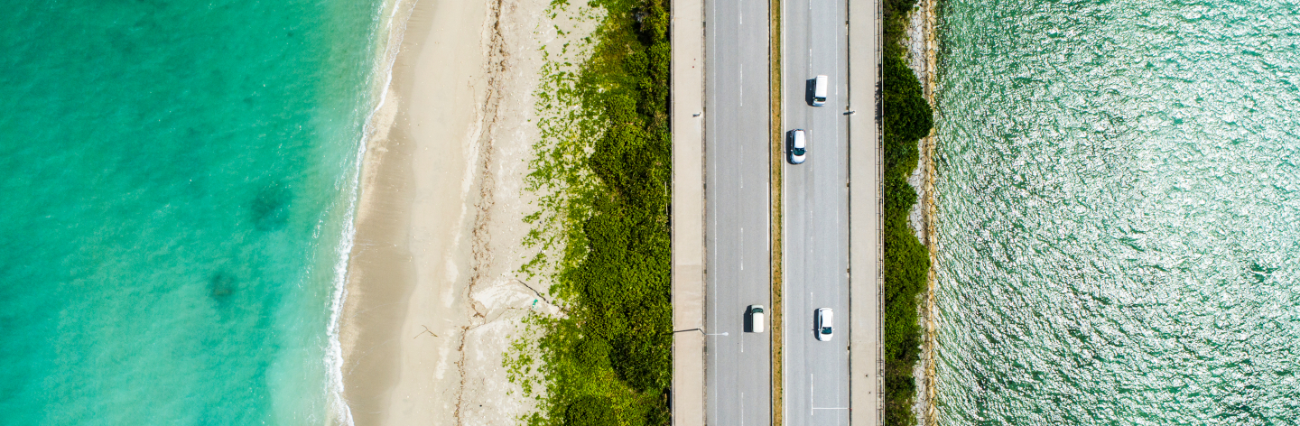 Aerial View Of Linear Road And Blue Sea.