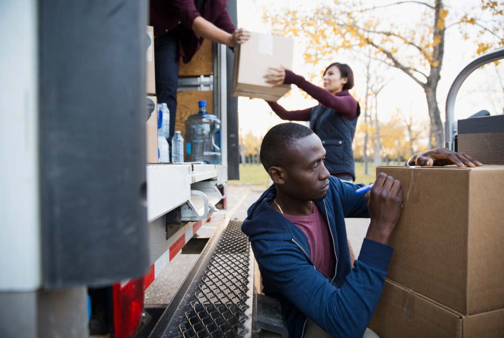 Volunteer Writing On Cardboard Box Outside Truck