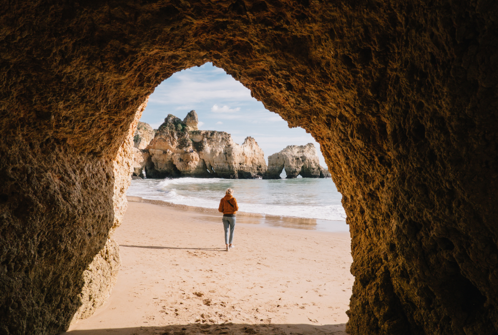 Woman Walking At Beach Seen Through Cave