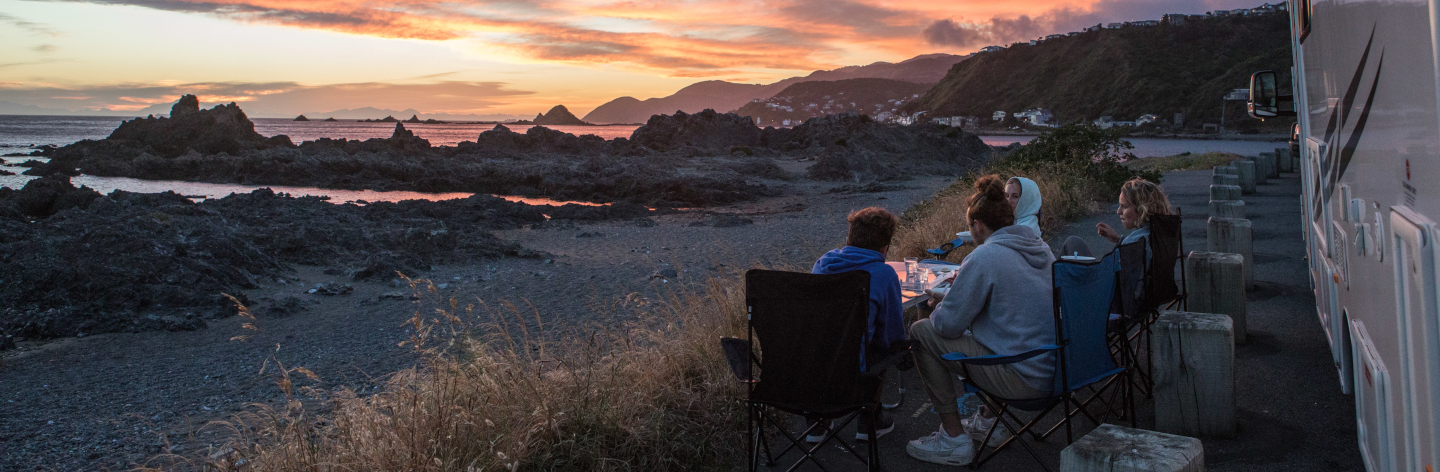 Friends On Road By Camper Van Against Sky During Sunset