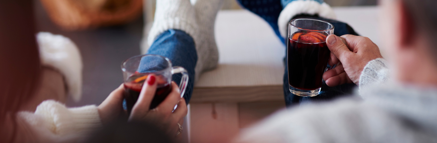 Mature Couple With Hot Drinks In Living Room At The Fireplace