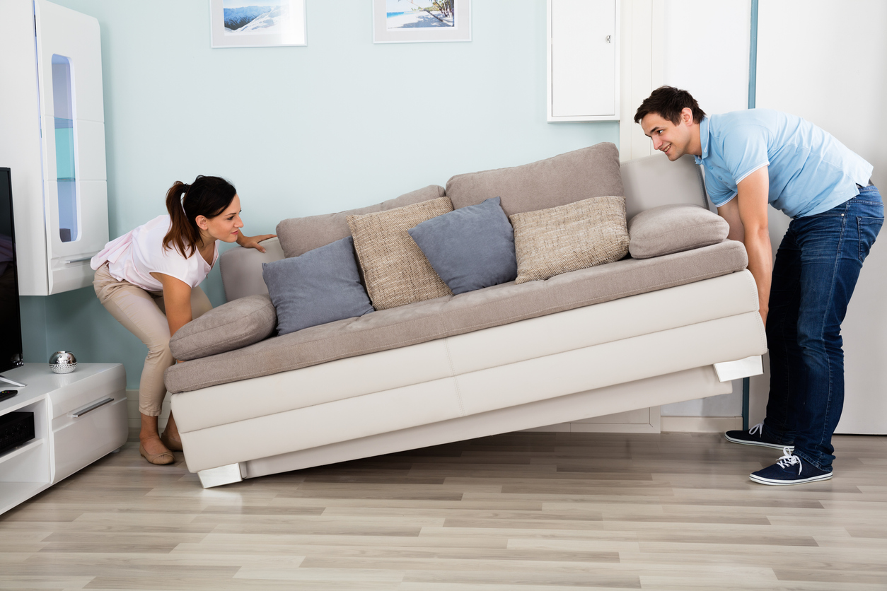 Couple Placing Sofa In Living Room