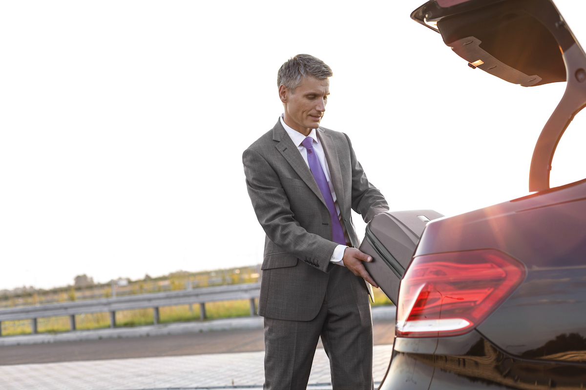 Businessman Taking Suitcase Out Of Car Boot