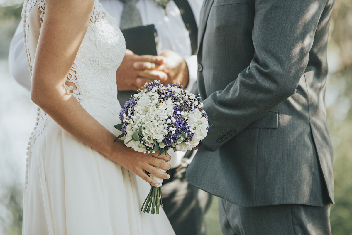 Bride And Groom Saying Vows During Wedding Ceremony Outdoors