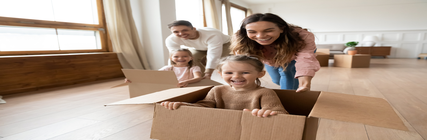 Happy Parents Playing With Little Kids Riding In Box