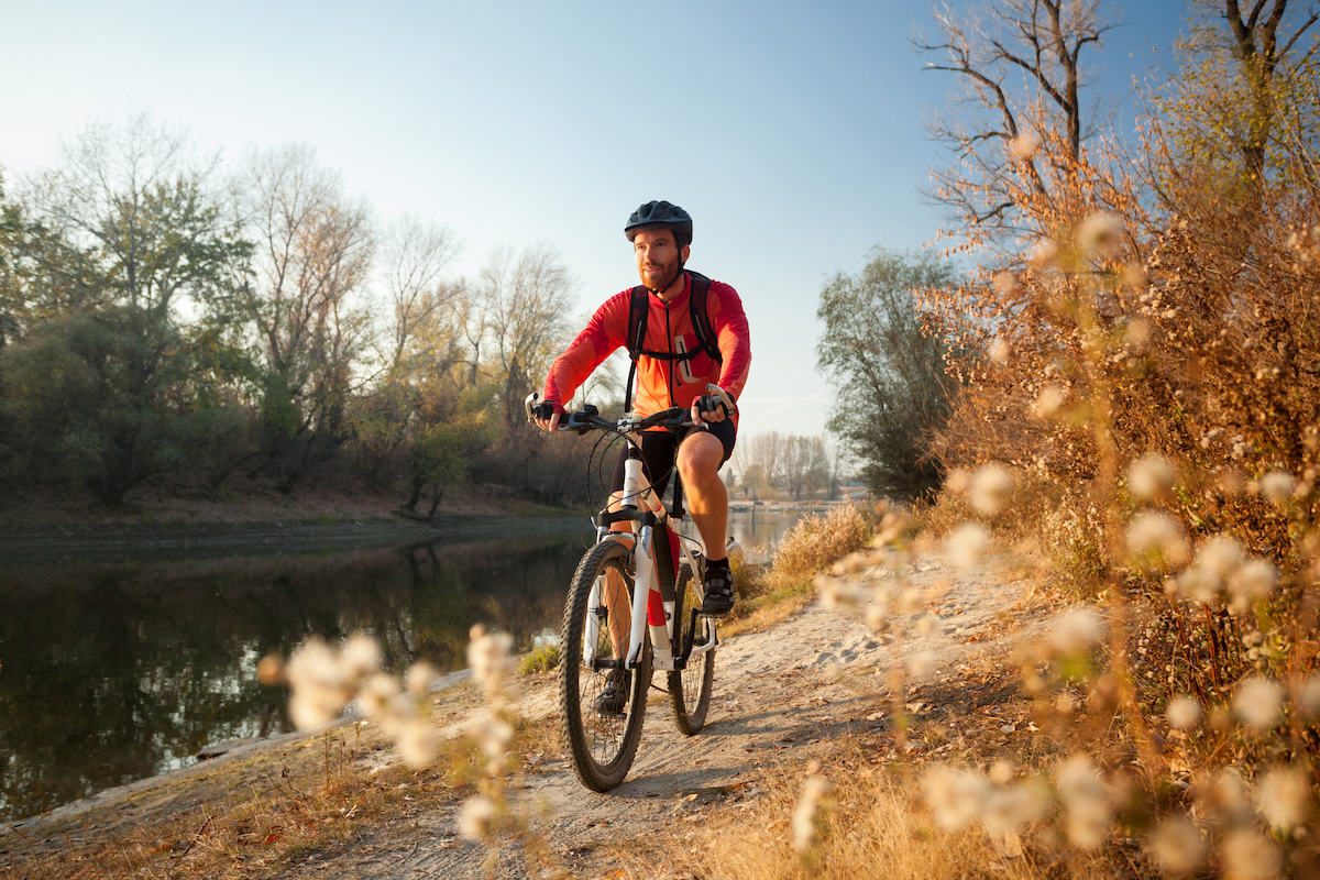 http://Happy%20Young%20Man%20Enjoying%20Late%20Afternoon%20Mountain%20Bike%20Ride%20By%20The%20River%20On%20A%20Clear%20Autumn%20Day