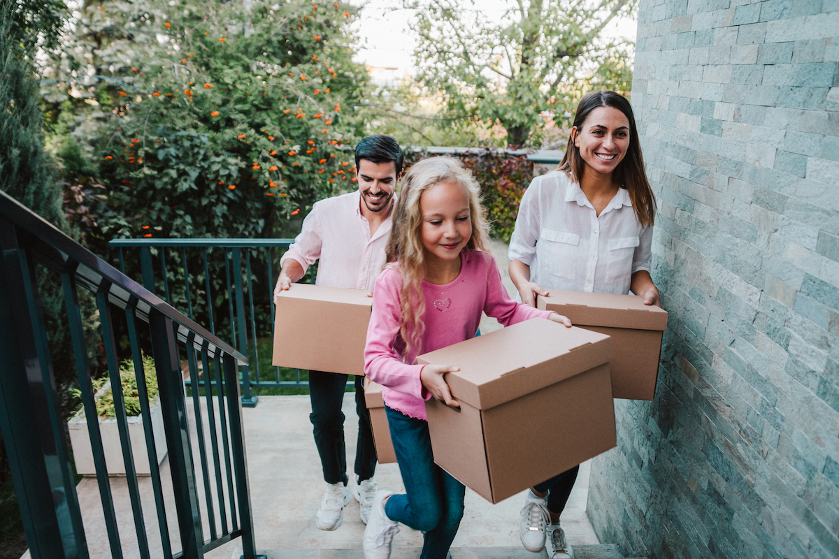 Smiling Family Carrying Boxes Into Their New House.