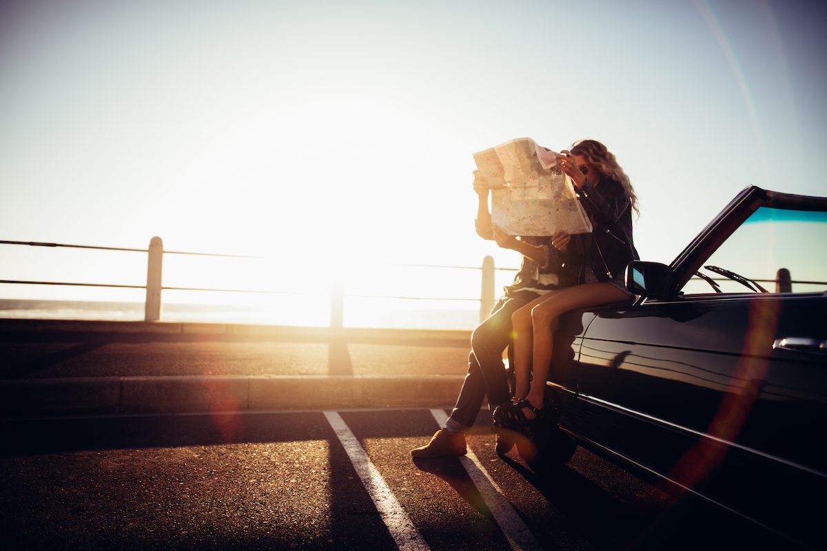 Hipster Couple Planning Their Summer Seaside Road Trip With Convertible