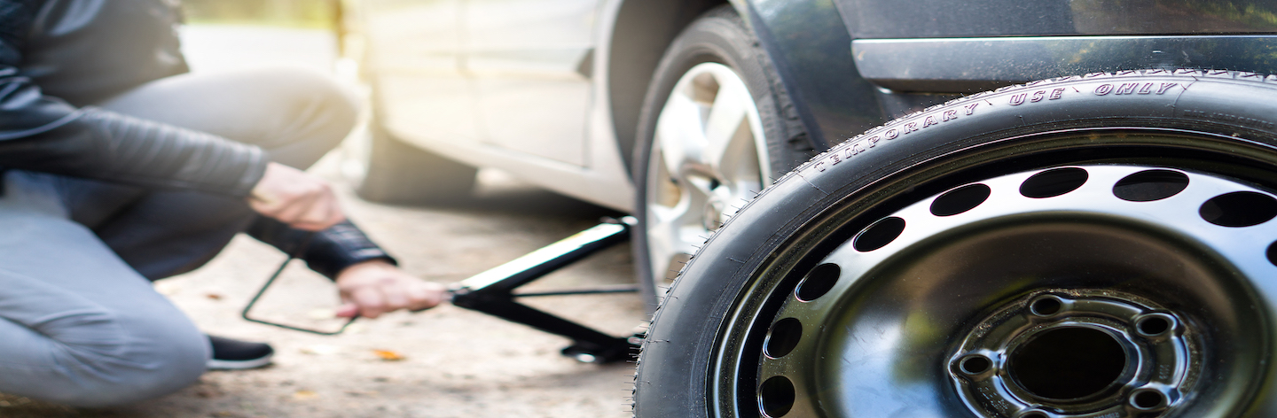 Driver Changing Spare Tyre After Accident. Broken And Flat Car Wheel After Crash. Man Fixing Problem With Jack.